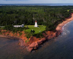 An aerial view of a picturesque coastal lighthouse, standing tall against the backdrop of the vast ocean.
