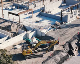 A construction site with a bulldozer and a crane working together to build structures.