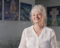 A woman with white hair sitting, looking relaxed and content.