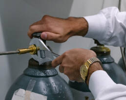 A man in a white shirt is repairing a gas cylinder.