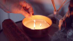 Three wick candle being lit with a match, creating a warm and cozy ambiance.