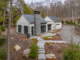 A picturesque bunkie featuring a stone pathway that leads to its welcoming front door, framed by vibrant landscaping.