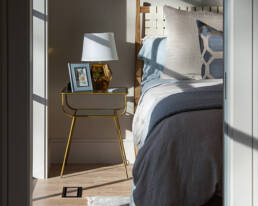 An inviting bedroom with a well-arranged bed and a decorative lamp situated on the floor nearby.