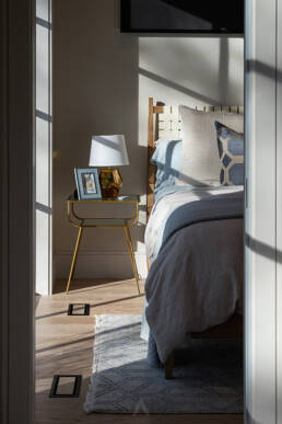 An inviting bedroom with a well-arranged bed and a decorative lamp situated on the floor nearby.