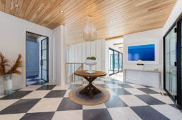 A white and black checkered floor beneath a rustic wooden ceiling, creating a striking contrast in the interior space.