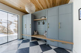 Interior view of a mud room showcasing a checkered floor and a wooden ceiling, highlighting a cozy design.