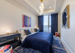 Contemporary bedroom with navy accents, abstract wall art, textured decor, and natural light captured with interior design photography.