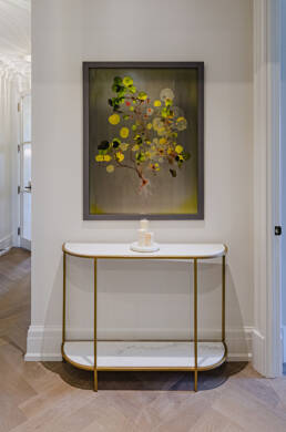 Modern hallway featuring a gold-framed marble console table, abstract botanical wall art, and candles, highlighted with expert interior design photography.